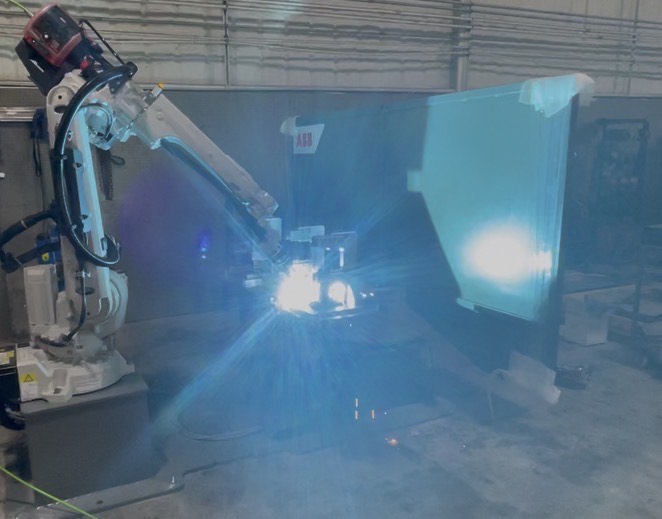 ABB robot mid-weld inside a United Robotics integration cell